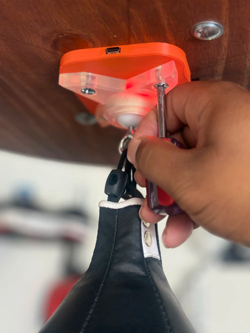 A hand turning a screwdriver to fit the orange counter under a speed bag platform