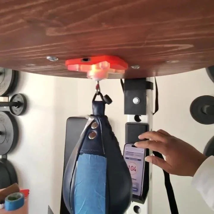 The counter under a speed bag platform, with the live count in the Speedbag Champ app on a phone